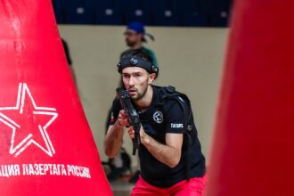 Игрок LASERWAR с автоматом у красного укрытия в движении.